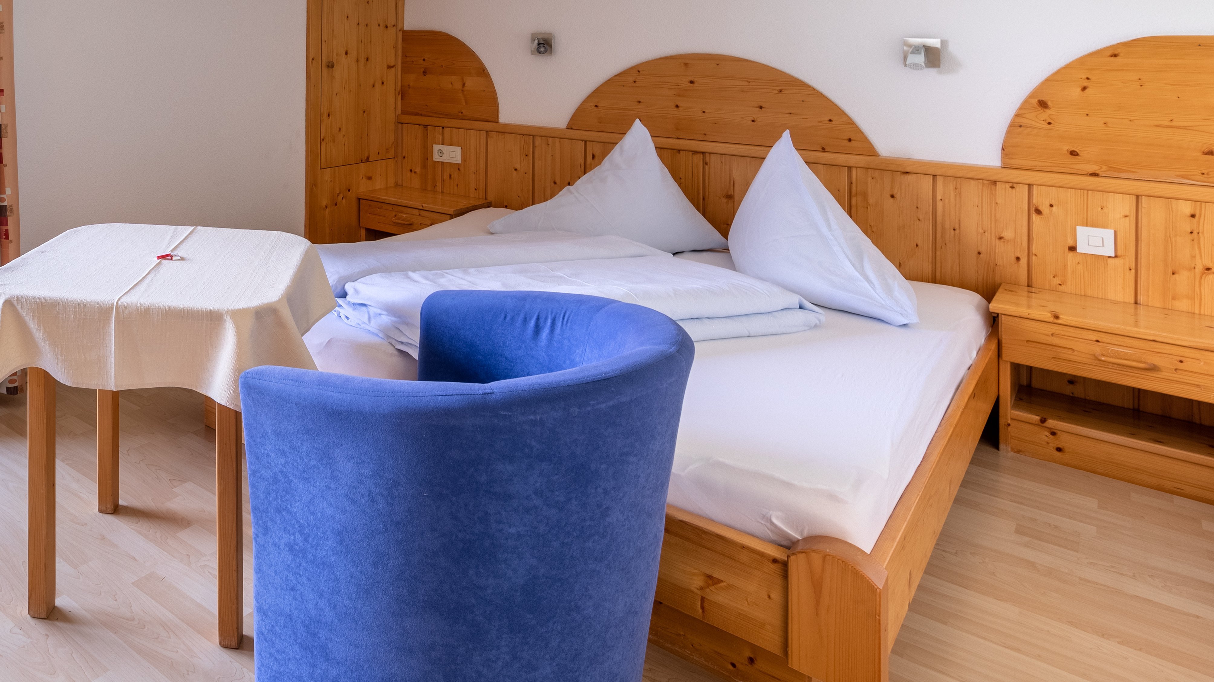 Ein einladendes Hotelzimmer mit großem Bett, Tisch und Stühlen sowie Fenster mit Blick auf die Berge.
