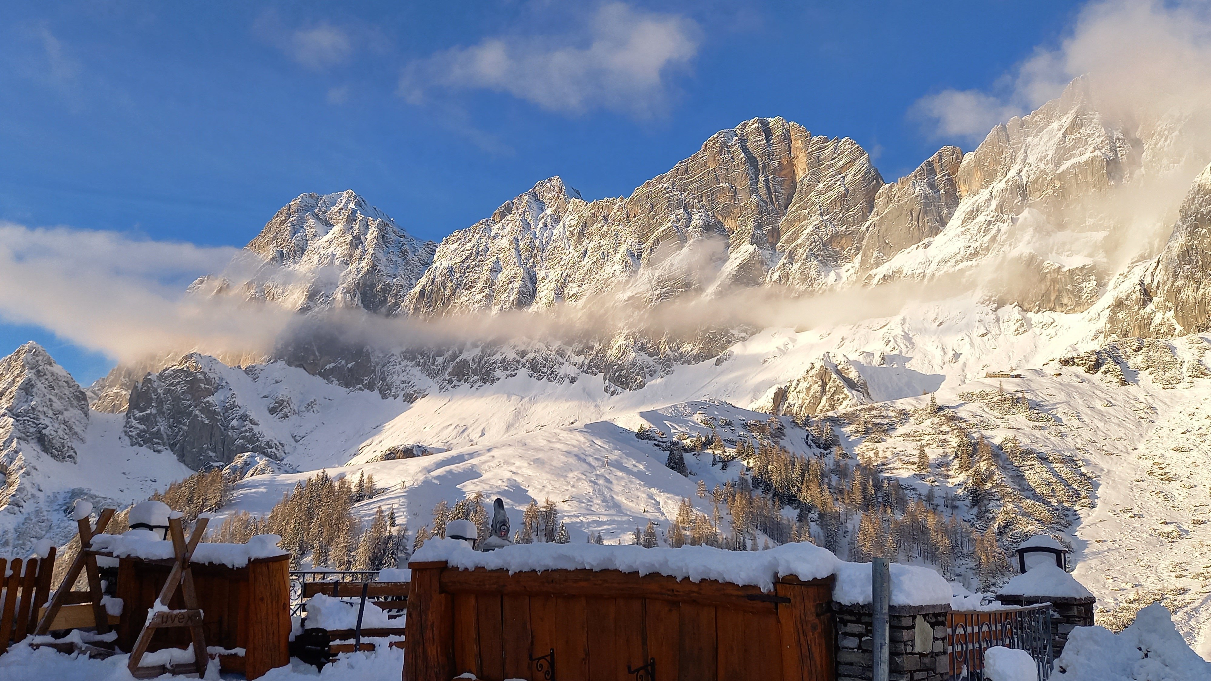 Snow-covered mountains under a clear blue sky with clouds in winter landscape scenery