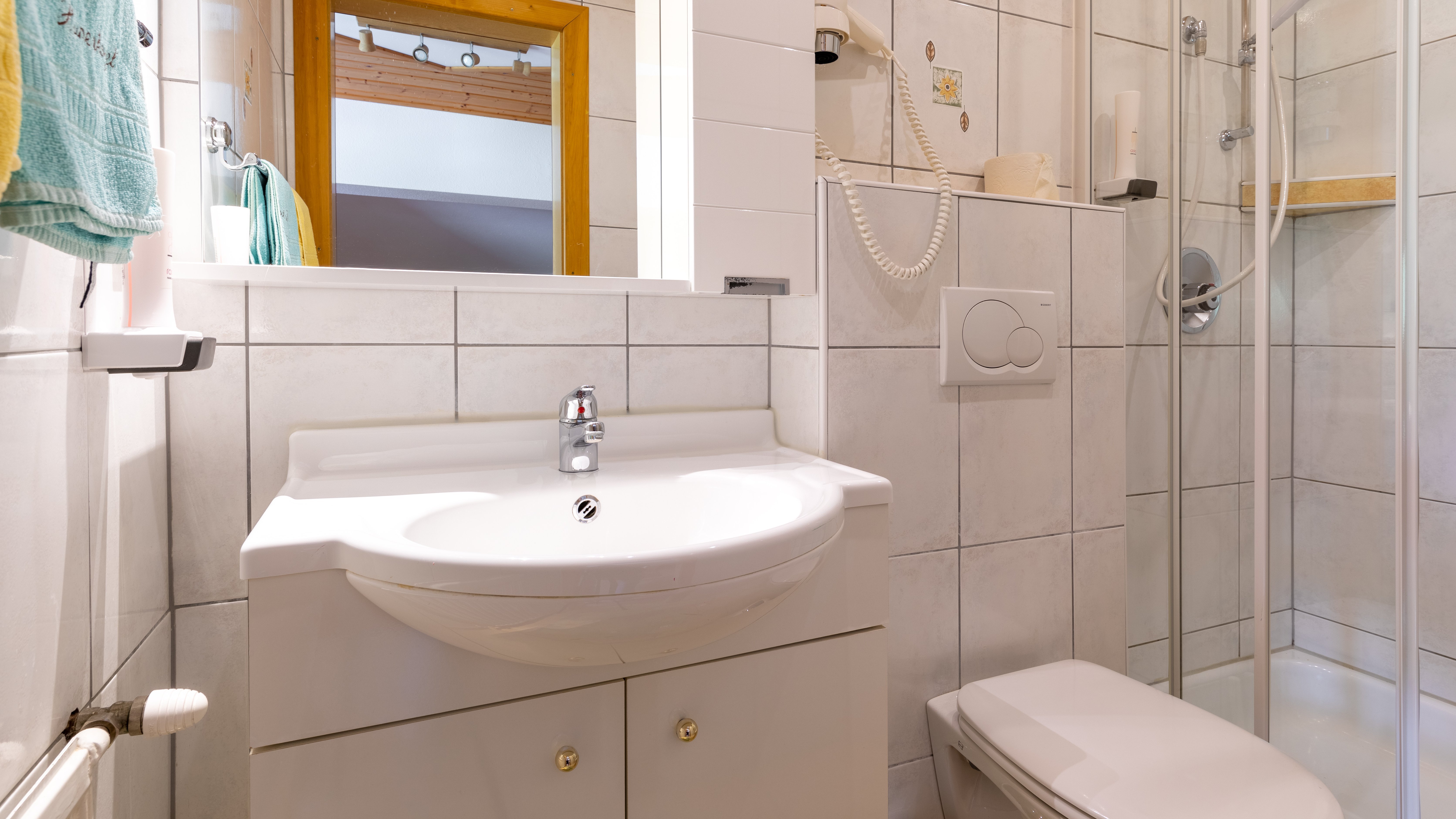 Ein modernes Badezimmer mit Dusche, Waschbecken und gefliesten Wänden sowie einem Spiegel