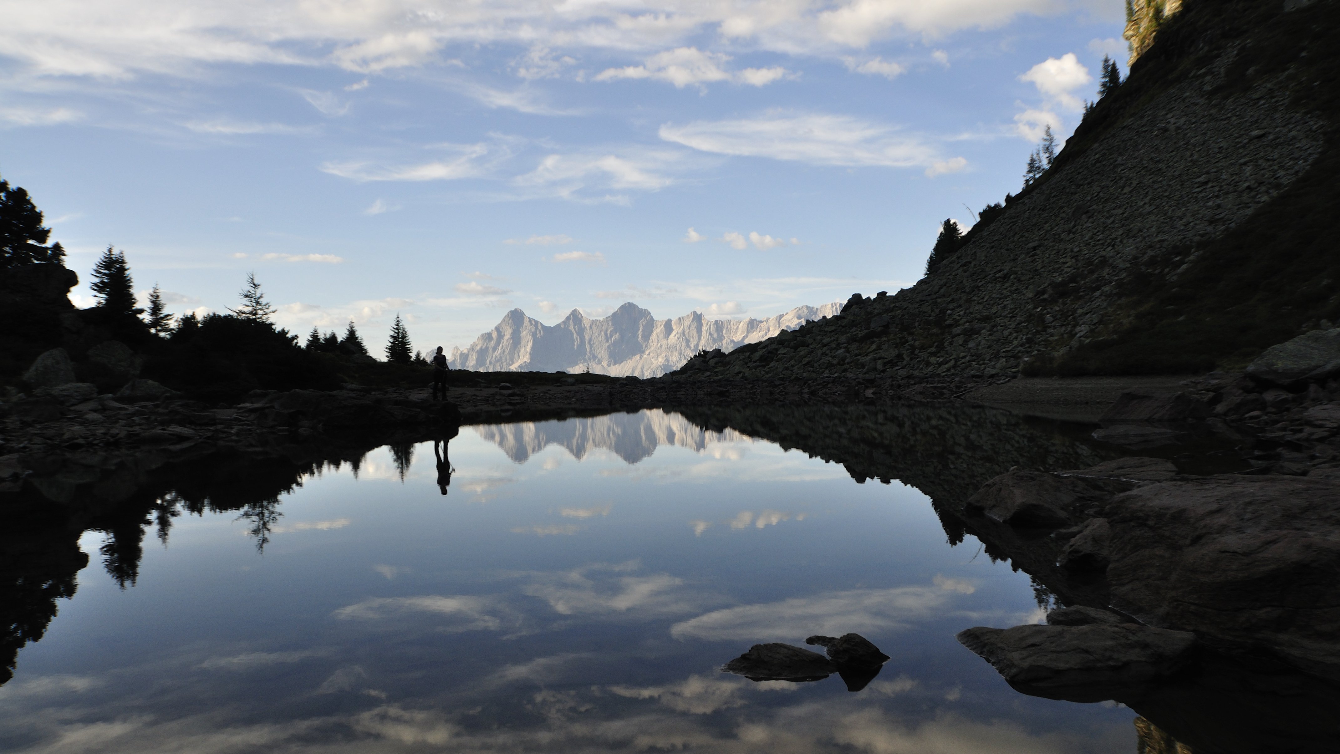 Ruhiger See mit Bergreflexion und klaren Himmel über der Wasseroberfläche bei Tageslicht
