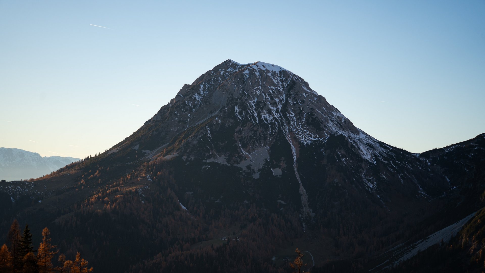 Berggipfel umgeben von Bäumen bei Sonnenuntergang im Freien sichtbar und Naturbelassen.