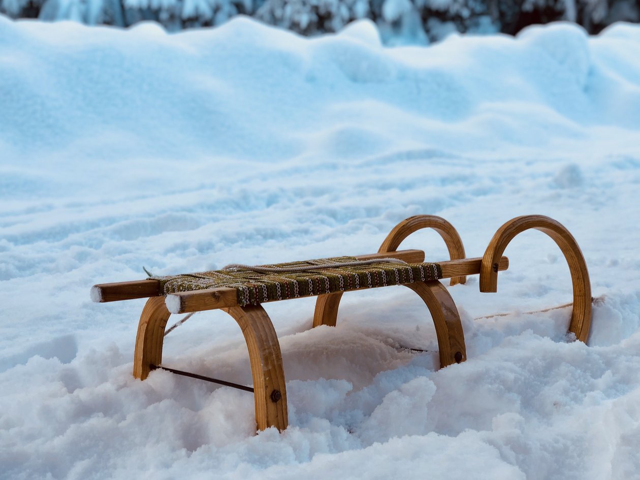 Winterfreude auf dem Schlitten Ein hölzerner Schlitten liegt in einer verschneiten Landschaft umgeben von frisch gefallenem Schnee.