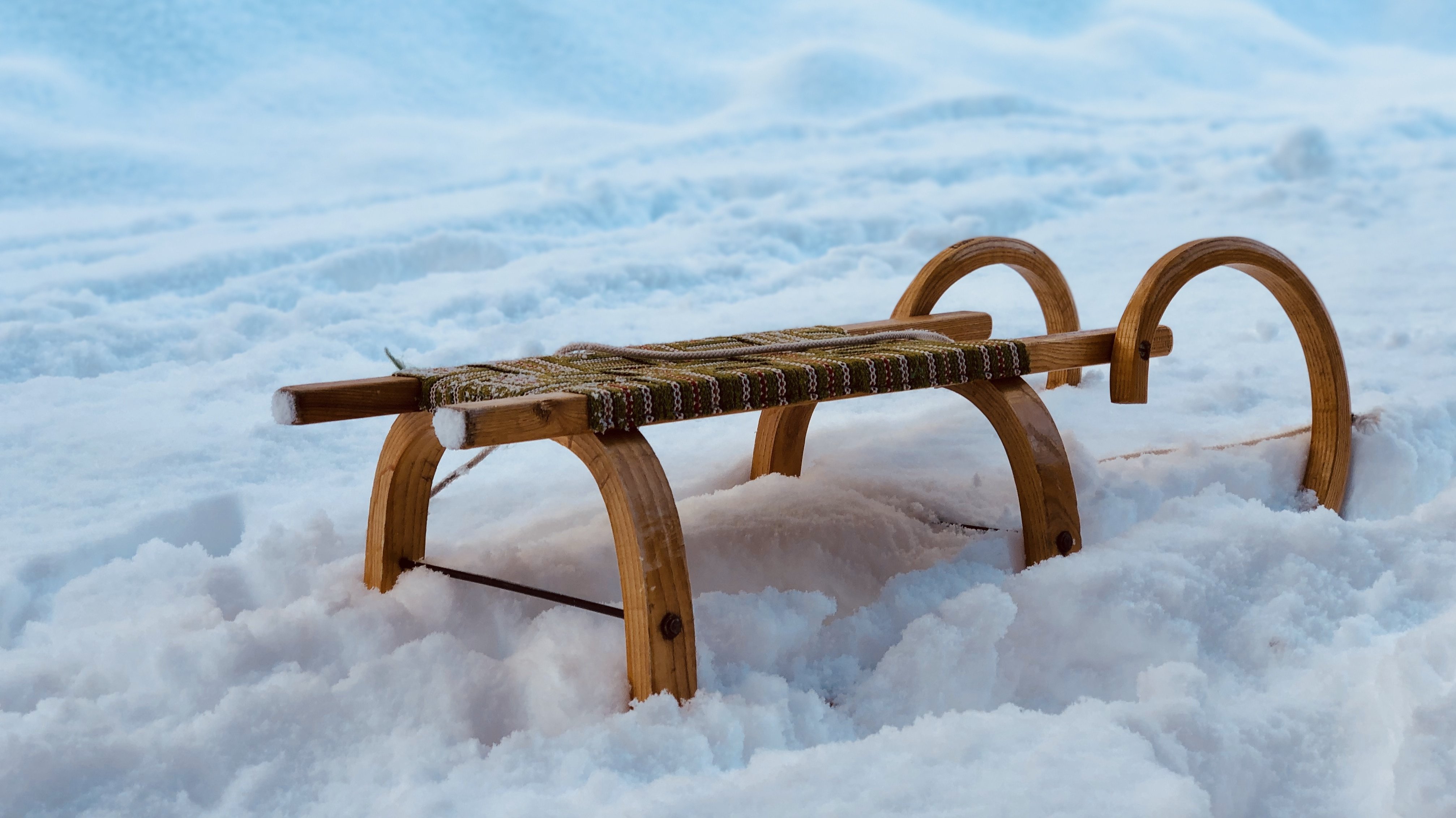 Ein hölzerner Schlitten liegt in einer verschneiten Landschaft umgeben von frisch gefallenem Schnee.