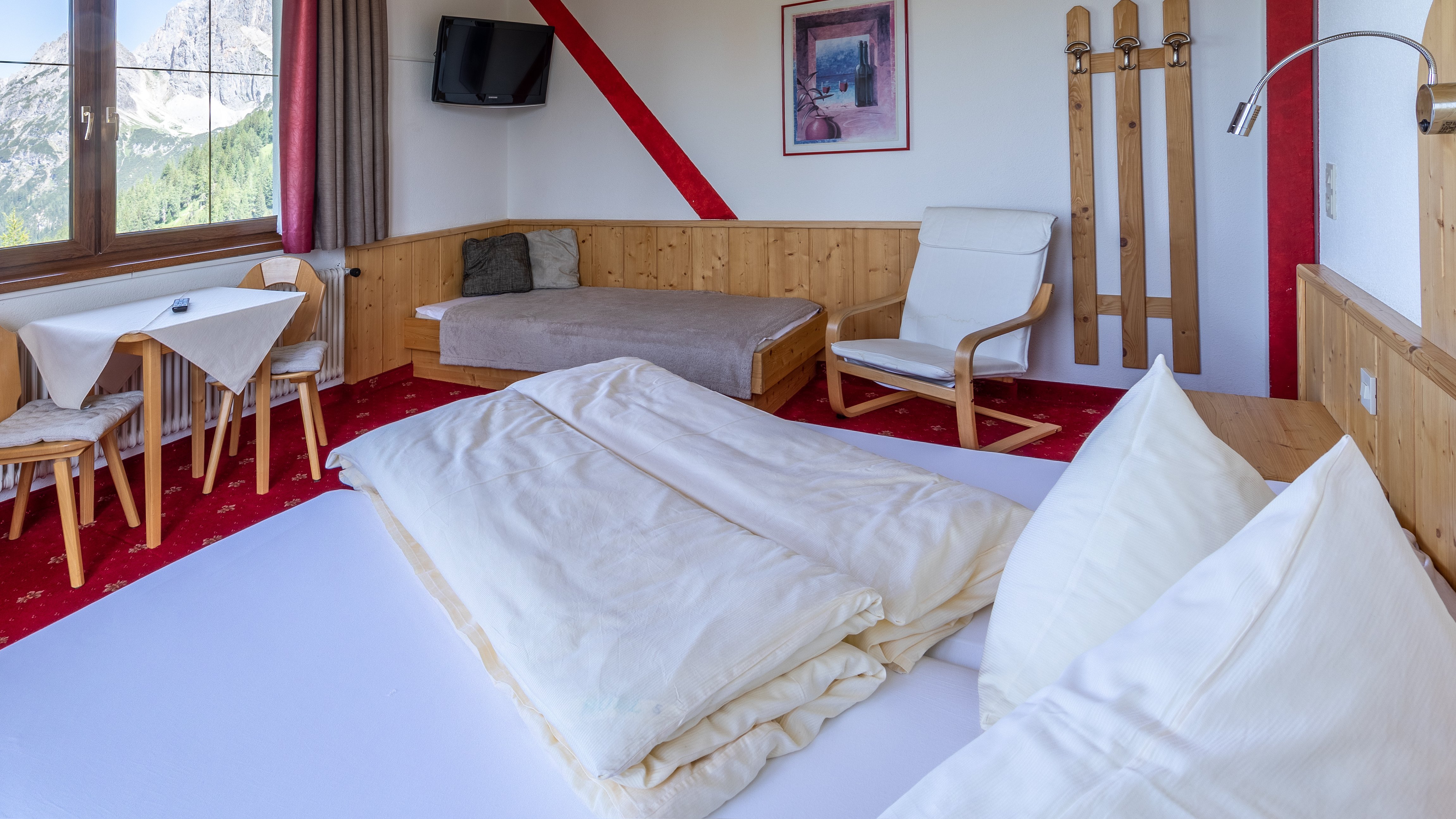 Hotelzimmer mit Holzverkleidung, Doppelbett und Sitzbereich sowie großem Fenster