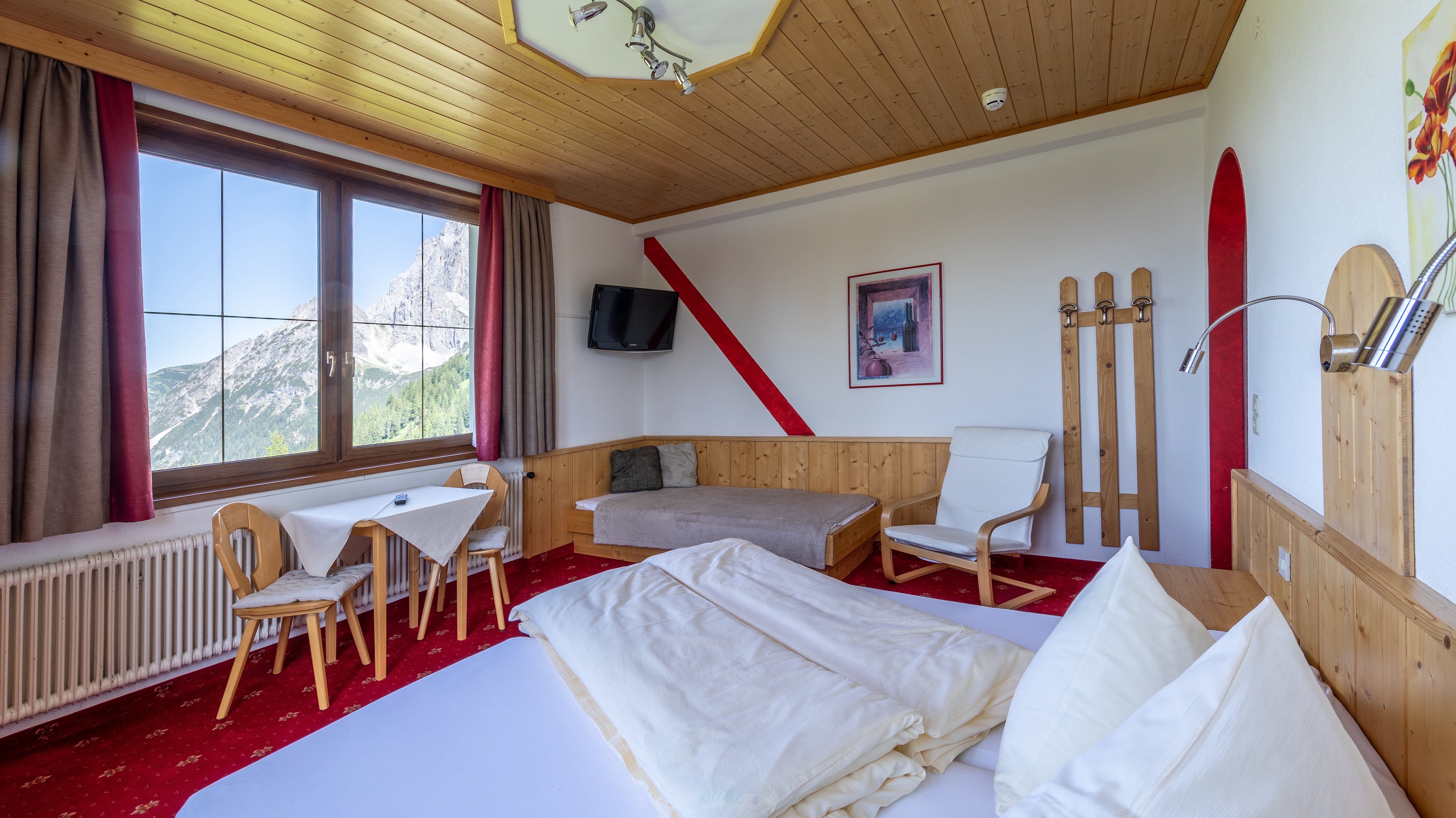 Hotelzimmer mit Holzverkleidung, Doppelbett und Sitzbereich sowie großem Fenster