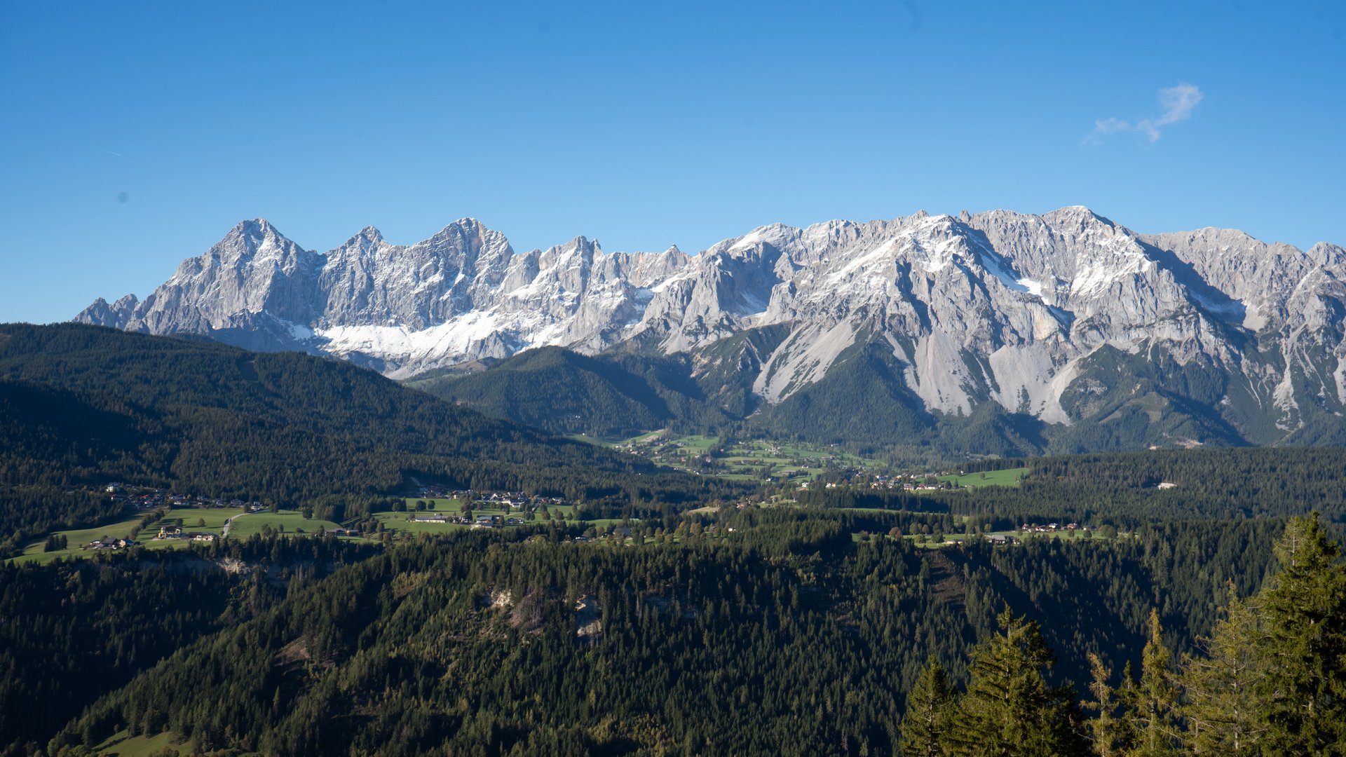 Bergpanorama mit schneebedeckten Gipfeln und grünem Tal im Vordergrund. Keine Menschen zu sehen.