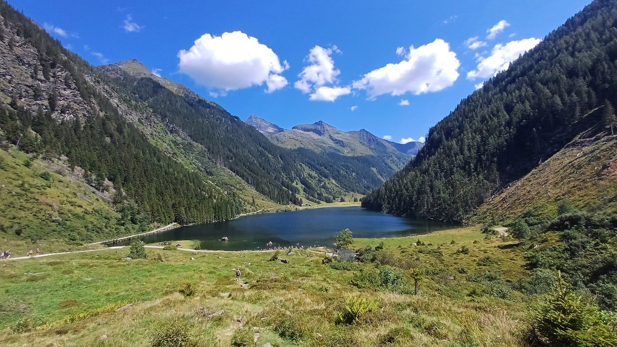 A serene lake surrounded by majestic mountains and lush greenery under a clear sky