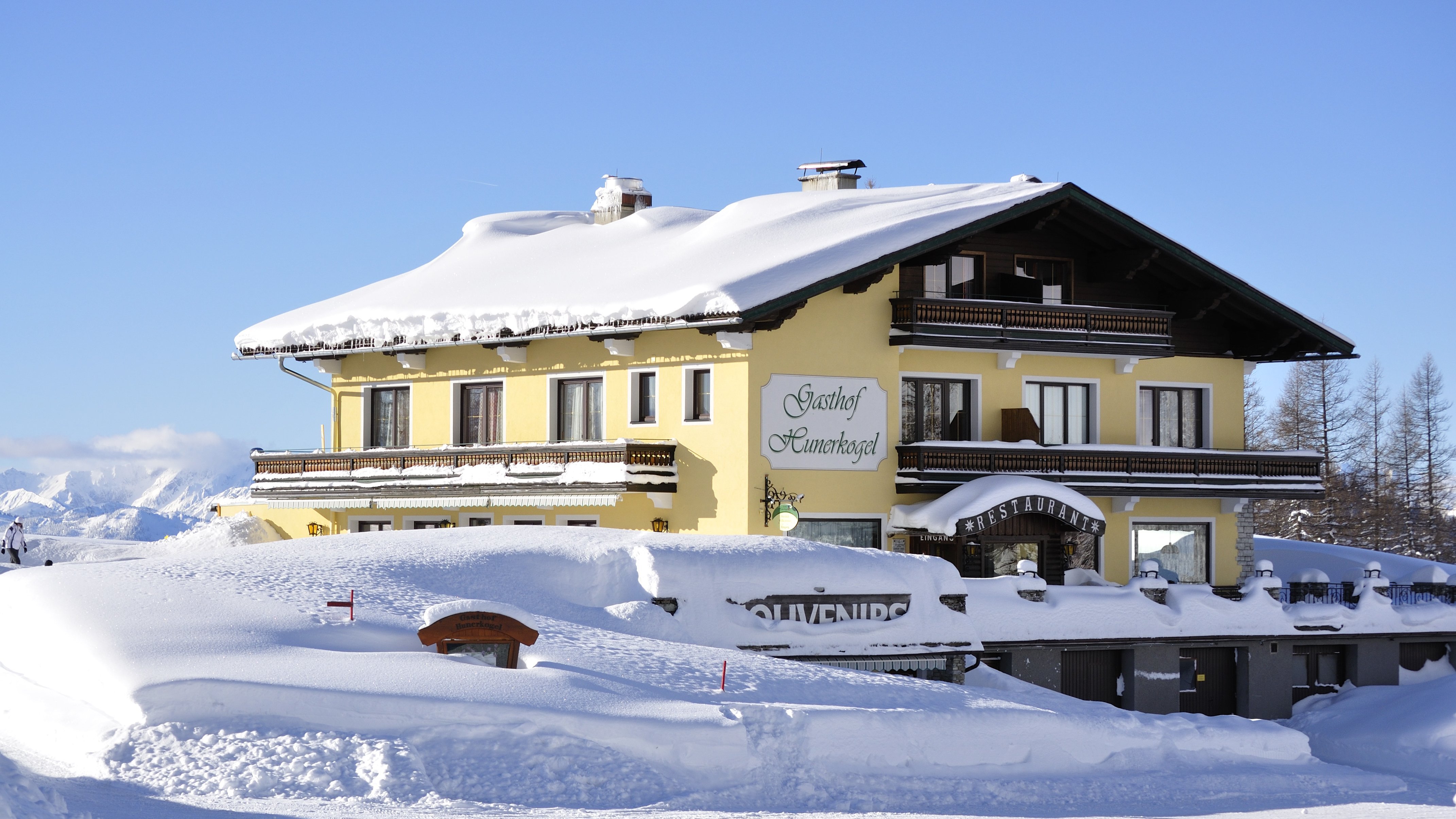 Alpenlodge im Wintertraum Schneebedecktes Gebäude im alpinen Stil in einer winterlichen Landschaft mit Bergen.