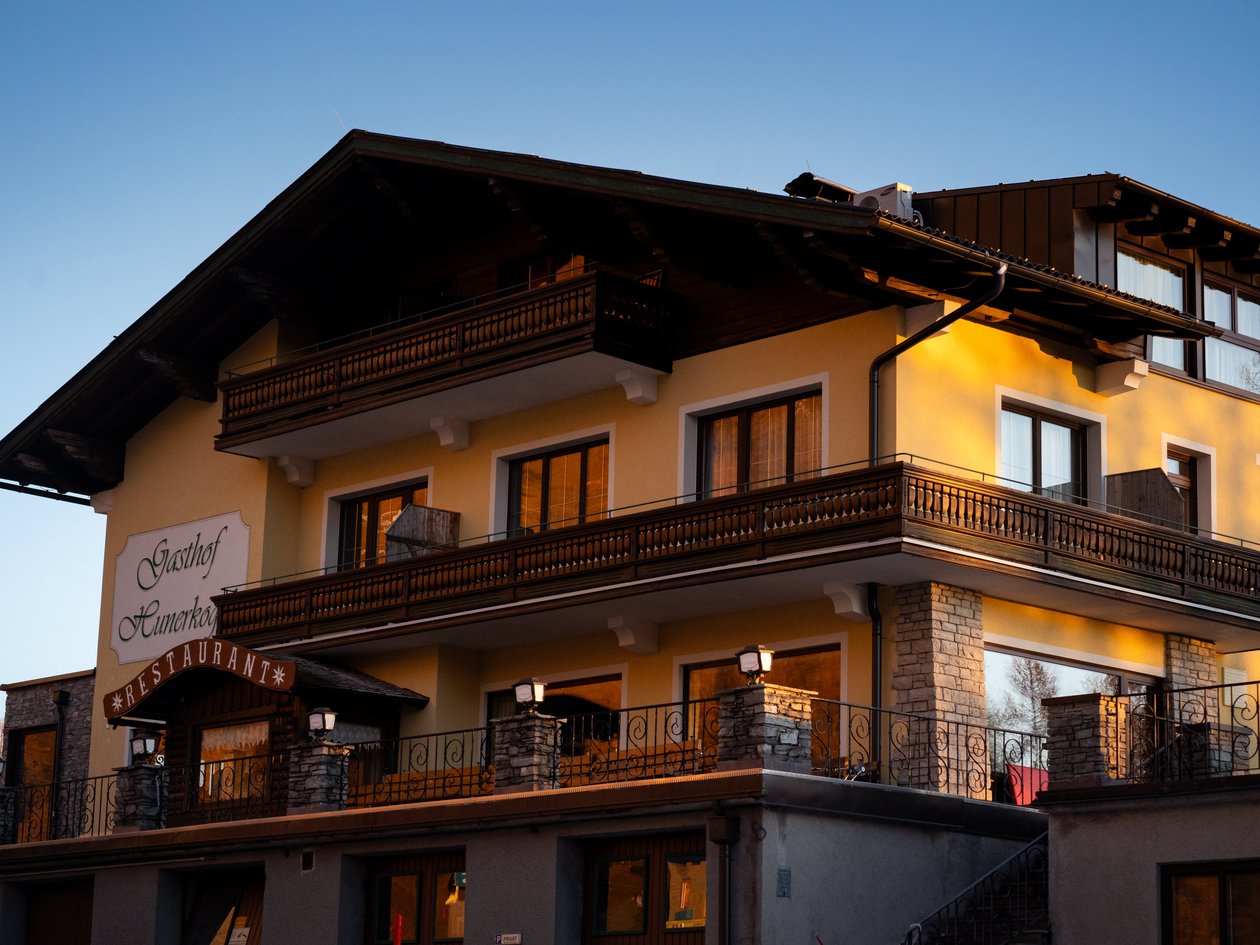 Einladendes Restaurant mit Balkonblick Mehrstöckiges Restaurantgebäude mit Holz- und Steinelementen in der Dämmerung, Balkone sichtbar