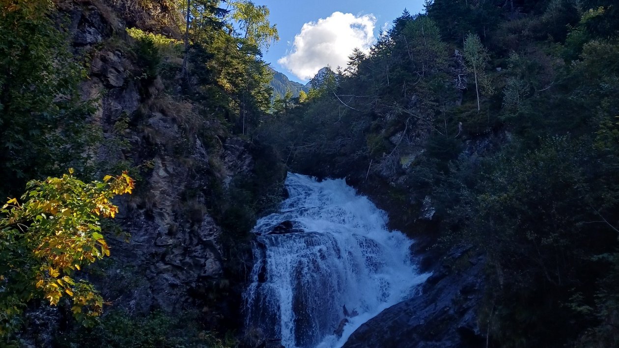 Wasserfall in traumhafter Landschaft Wasserfall fließt über Felsen, umgeben von üppigem Grün und klarem Himmel. Vegetation sorgt für natürliche Schönheit.