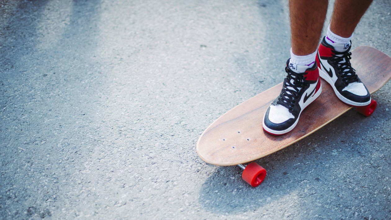 Skateboard Abenteuer in der Stadt Person steht auf einem Skateboard und trägt auffällige Sneakers in einem urbanen Umfeld.