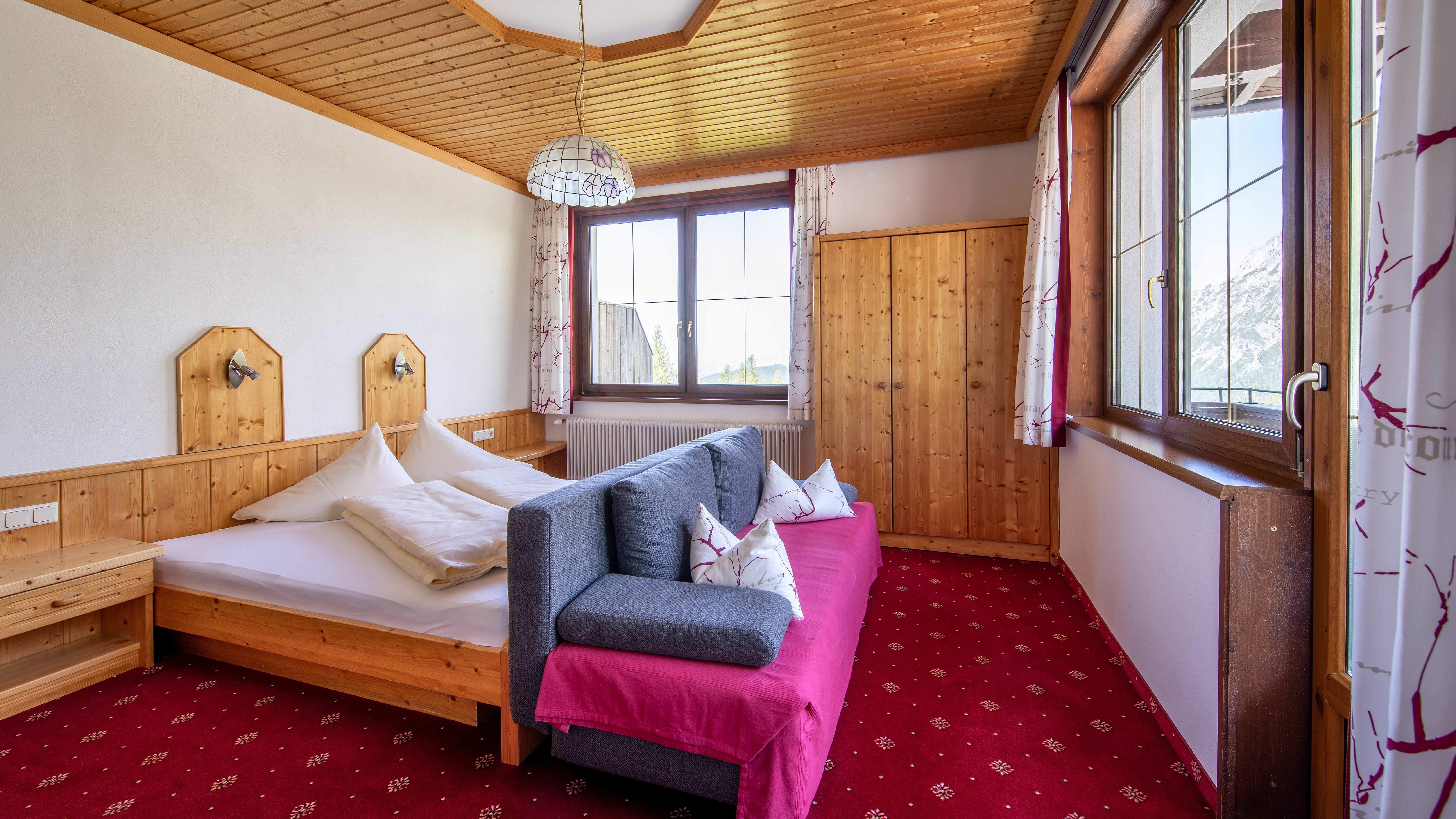 Hotelzimmer mit Holz Möbeln, Doppelbett und Sitzbereich sowie Aussicht auf die Berge