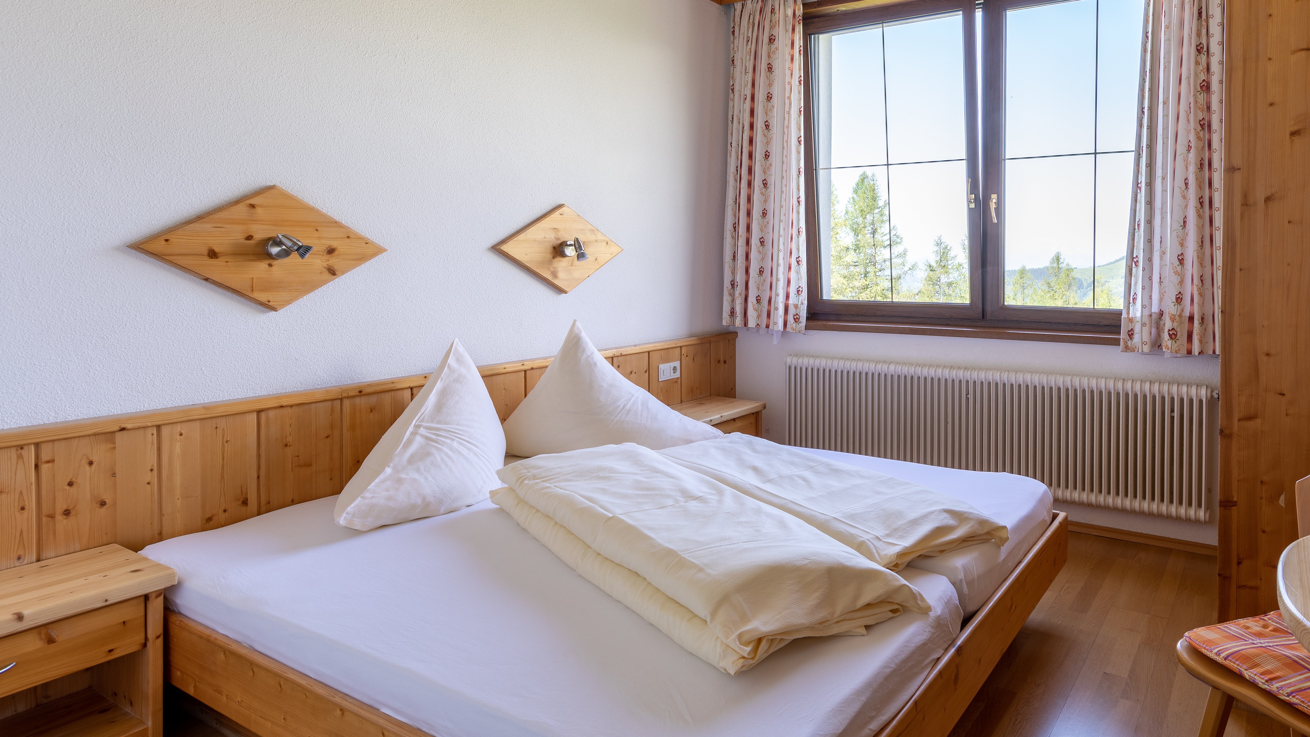 Hotelzimmer mit Holzinterieur und Blick auf die Berge durch ein großes Fenster, ordentliches Bett.