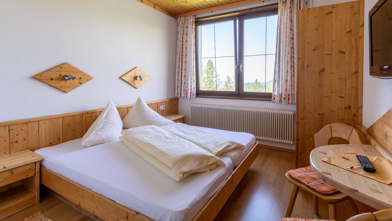Gemütliches Zimmer mit Bergblick Hotelzimmer mit Holzinterieur und Blick auf die Berge durch ein großes Fenster, ordentliches Bett.