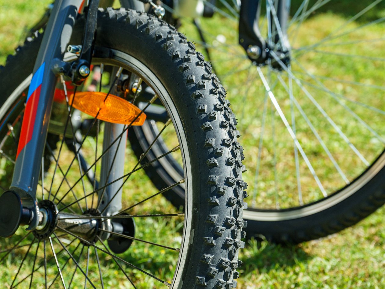 Bergabenteuer mit dem Mountainbike Nahaufnahme eines Mountainbike-Reifens auf Gras mit gut erkennbarem Profil und Radkomponenten