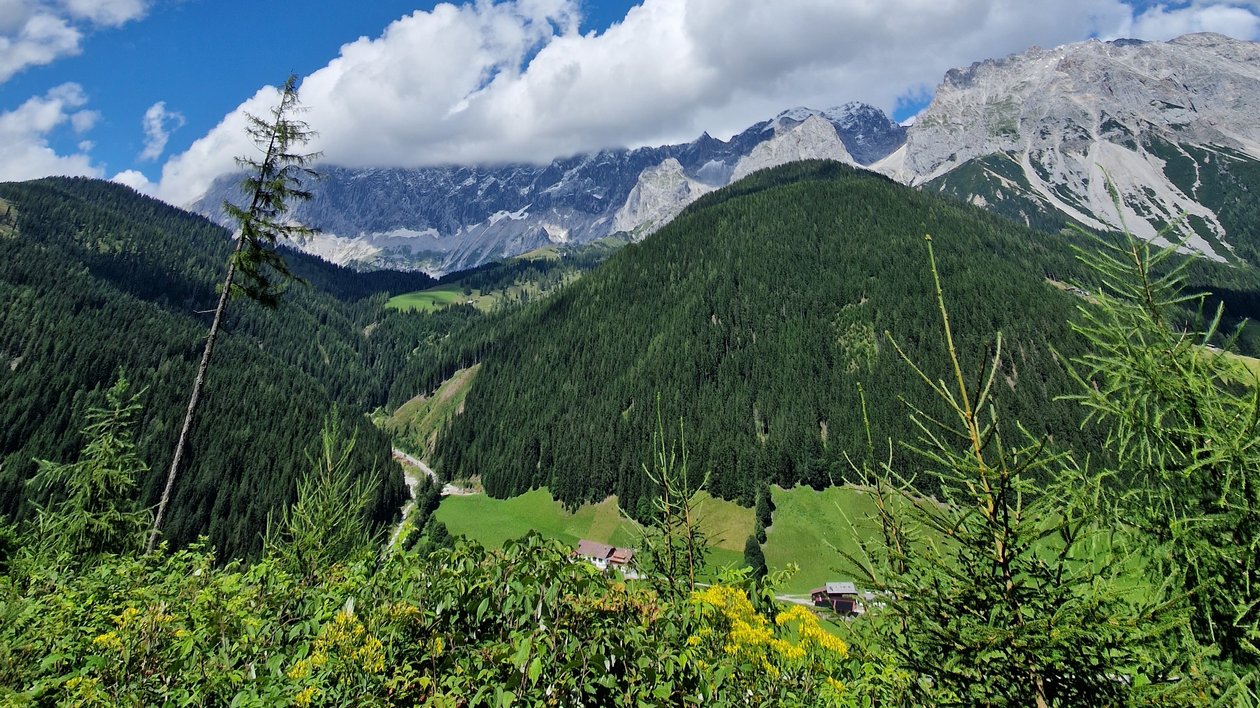 Berglandschaft unter blauem Himmel Panoramablick auf eine grüne Berglandschaft mit Wolken im Himmel und bewaldeten Tälern