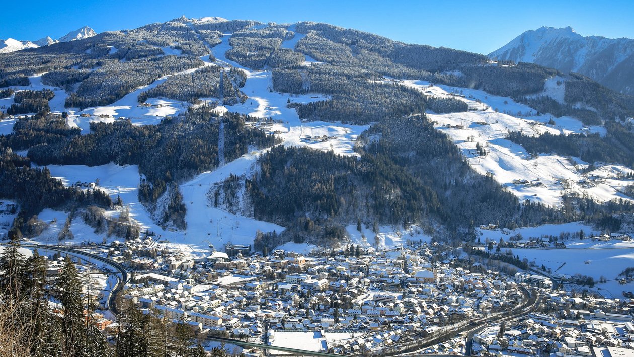 Winterzauber im Bergdorf Schneebedecktes Bergdorf in winterlicher Landschaft mit sichtbaren Skipisten im Hintergrund