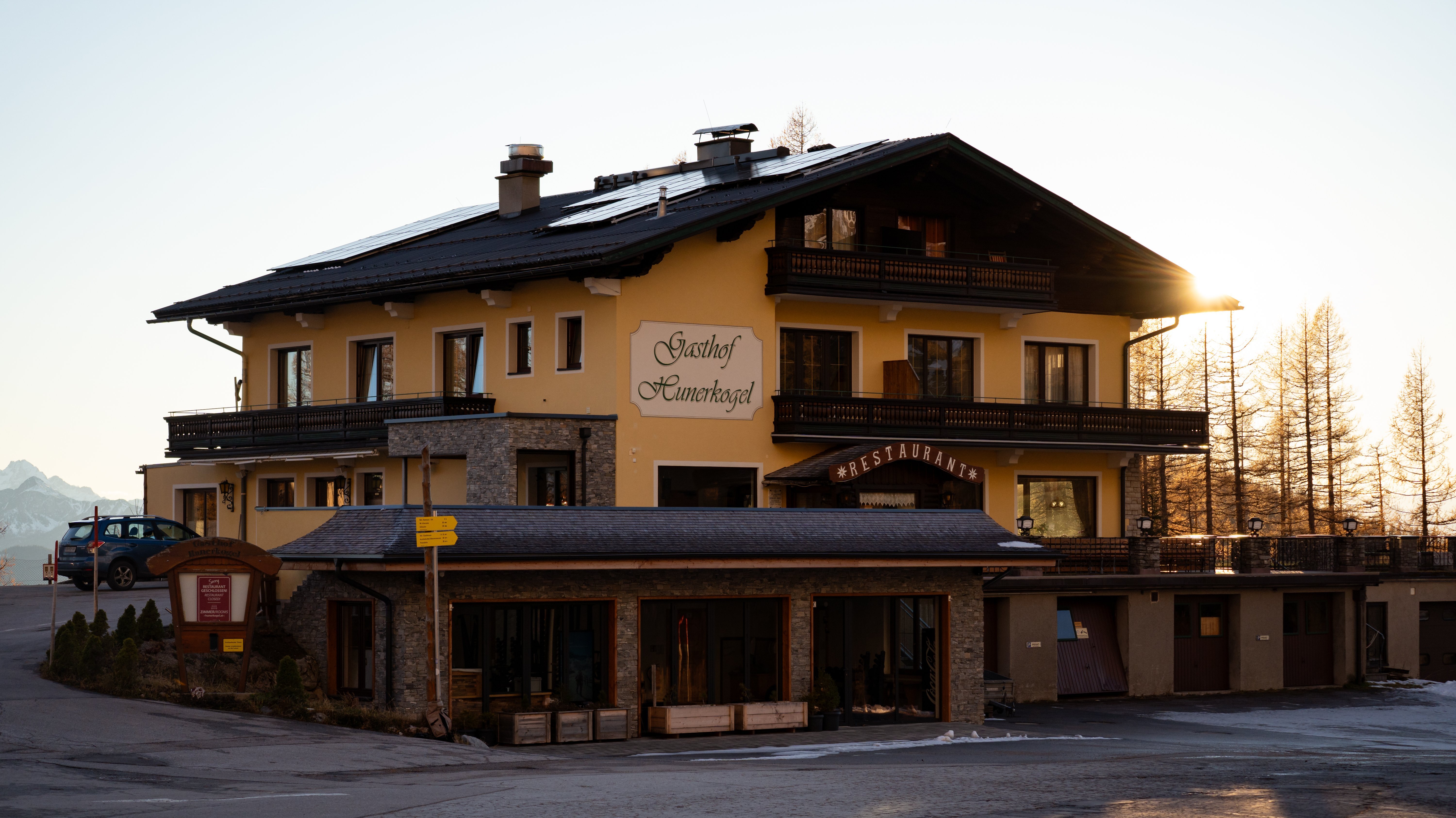 Berggasthof Hunerkogel bei Sonnenuntergang Berggasthof mit traditioneller und moderner Architektur im Abendlicht, umgeben von Bergen.