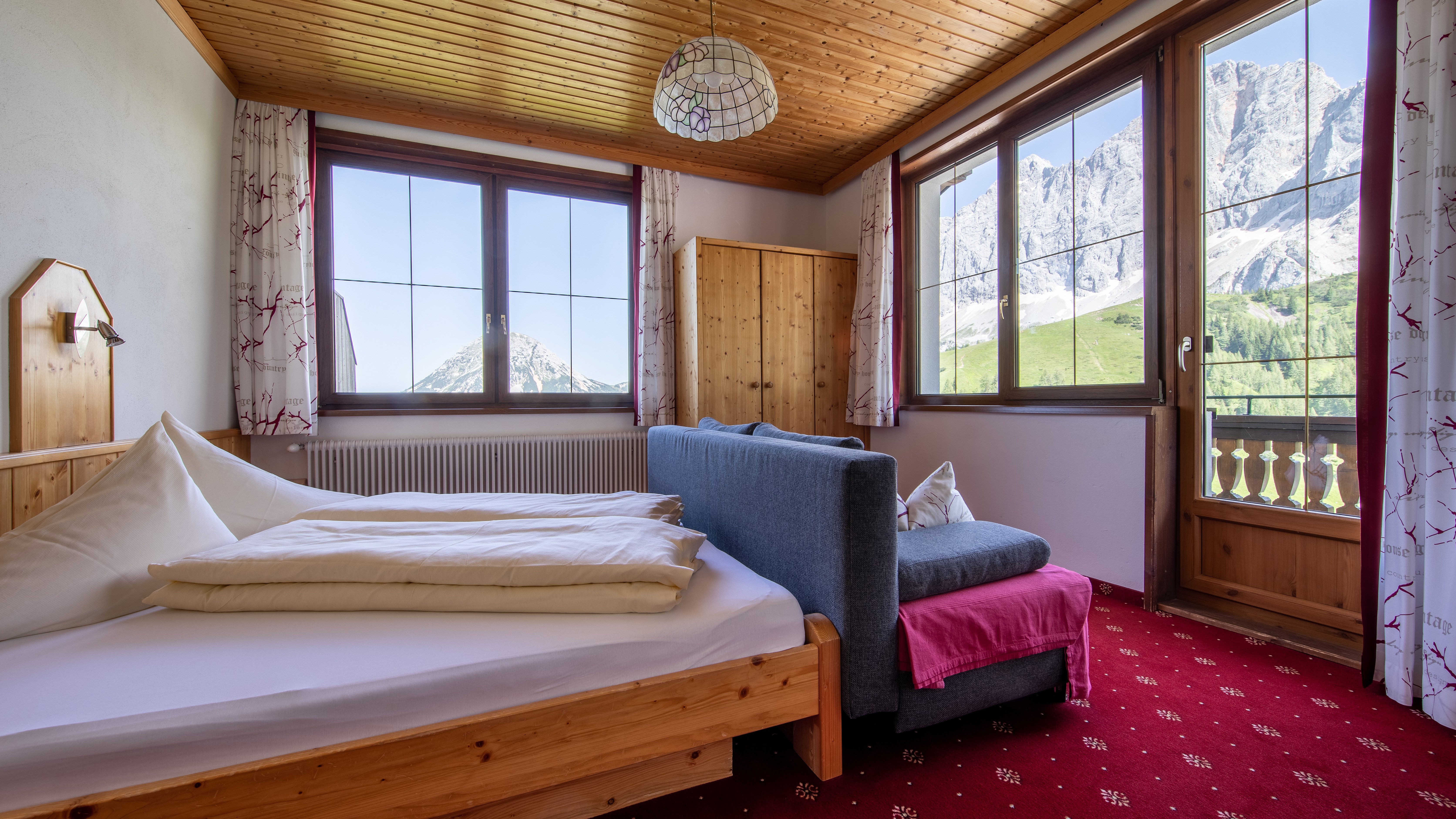 Ein einladendes Schlafzimmer mit Holzelementen, einem Bett und großen Fenstern zur Berglandschaft.