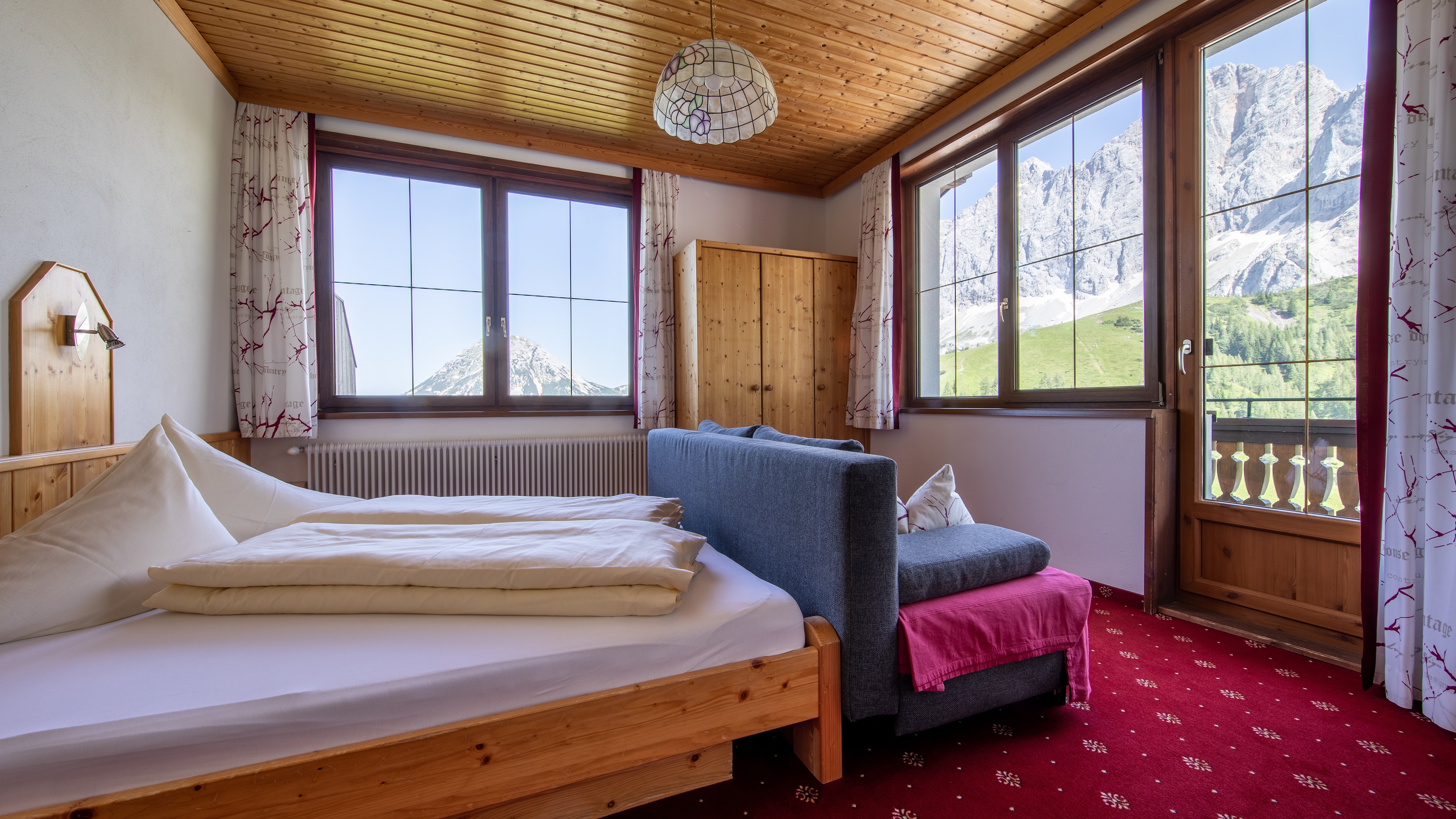 Ein einladendes Schlafzimmer mit Holzelementen, einem Bett und großen Fenstern zur Berglandschaft.