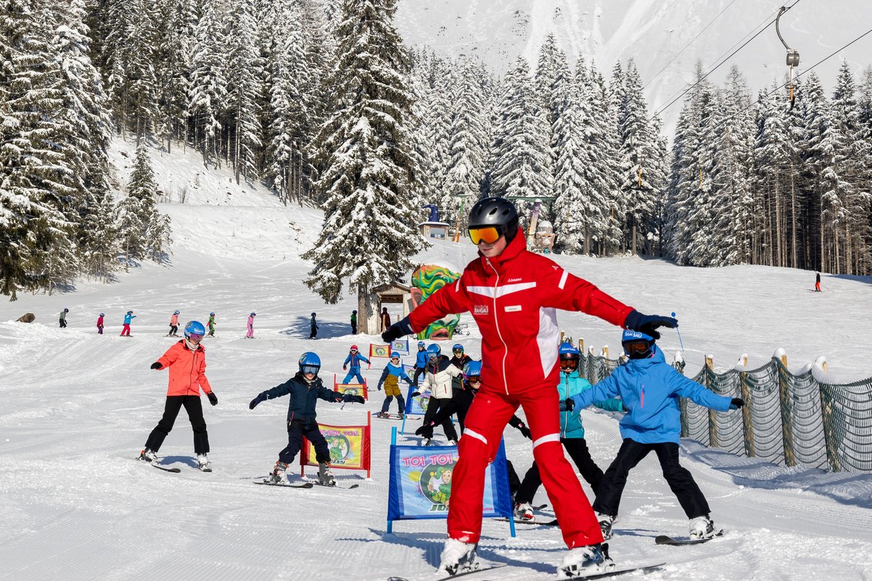 Schneevergnügen im Skigebiet Ramsau Skifahrer auf einer verschneiten Piste umgeben von Bäumen und Bergen im Hintergrund
