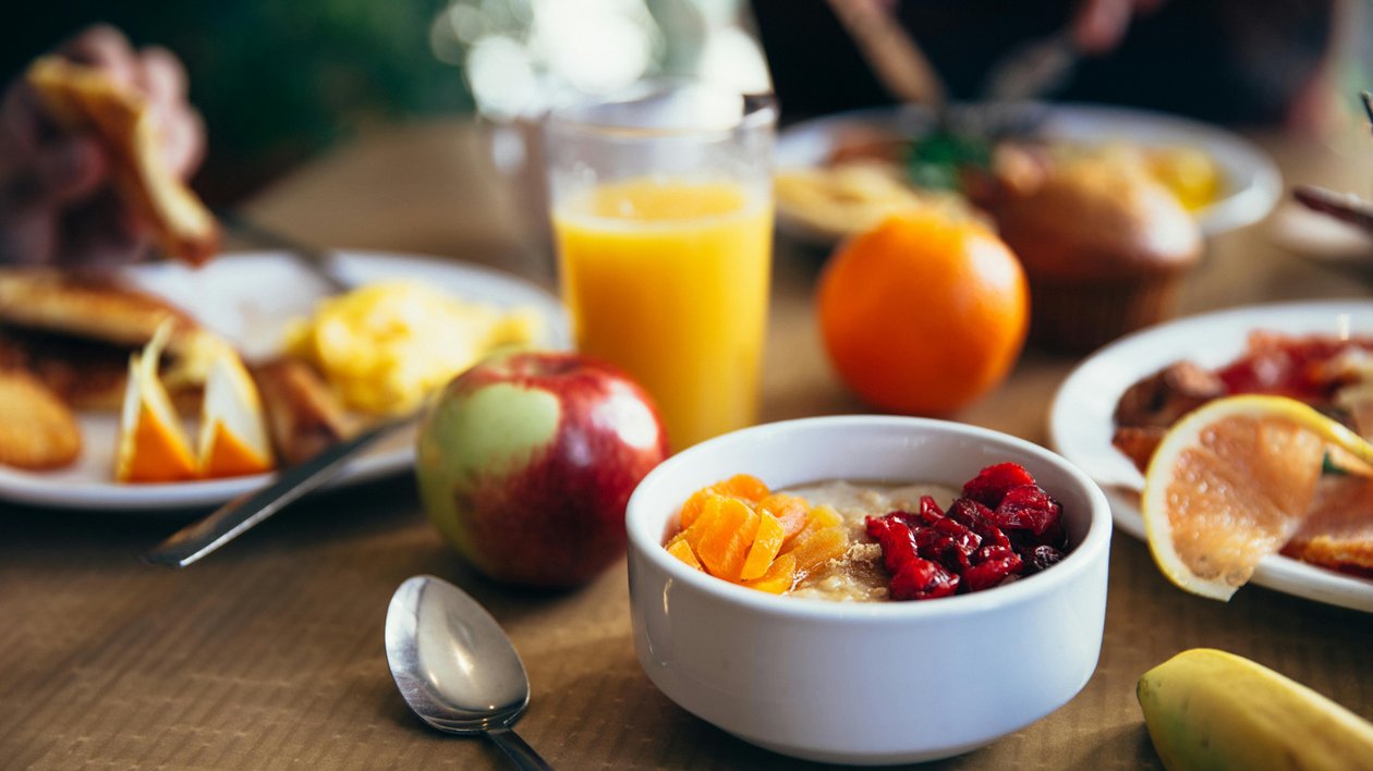 Eine Auswahl an gesundem Frühstück mit Haferflocken, frischem Obst und Orangensaft