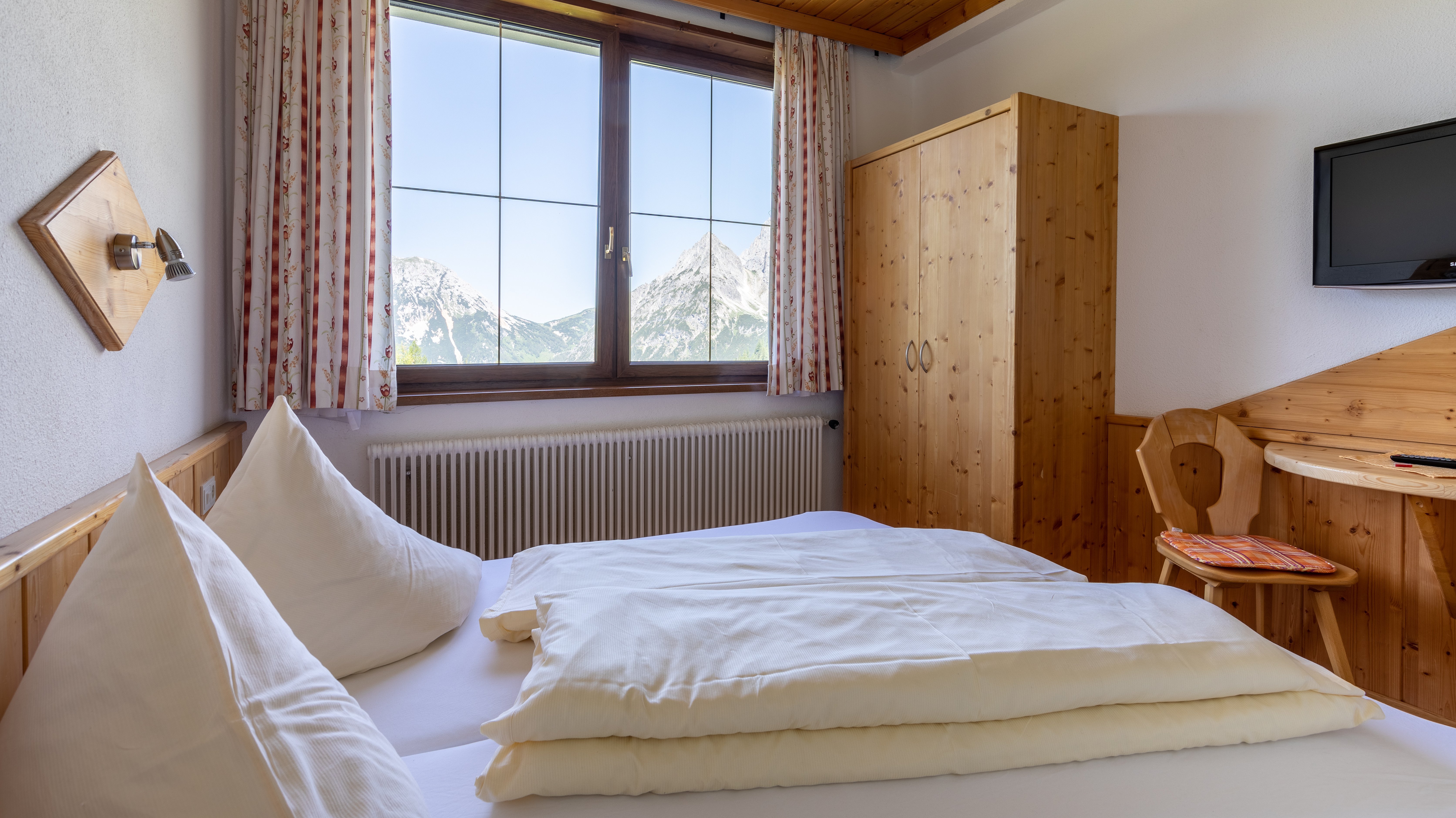 Gemütliches Hotelzimmer mit Doppelbett und großem Fenster mit Bergsicht in Ramsau am Dachstein