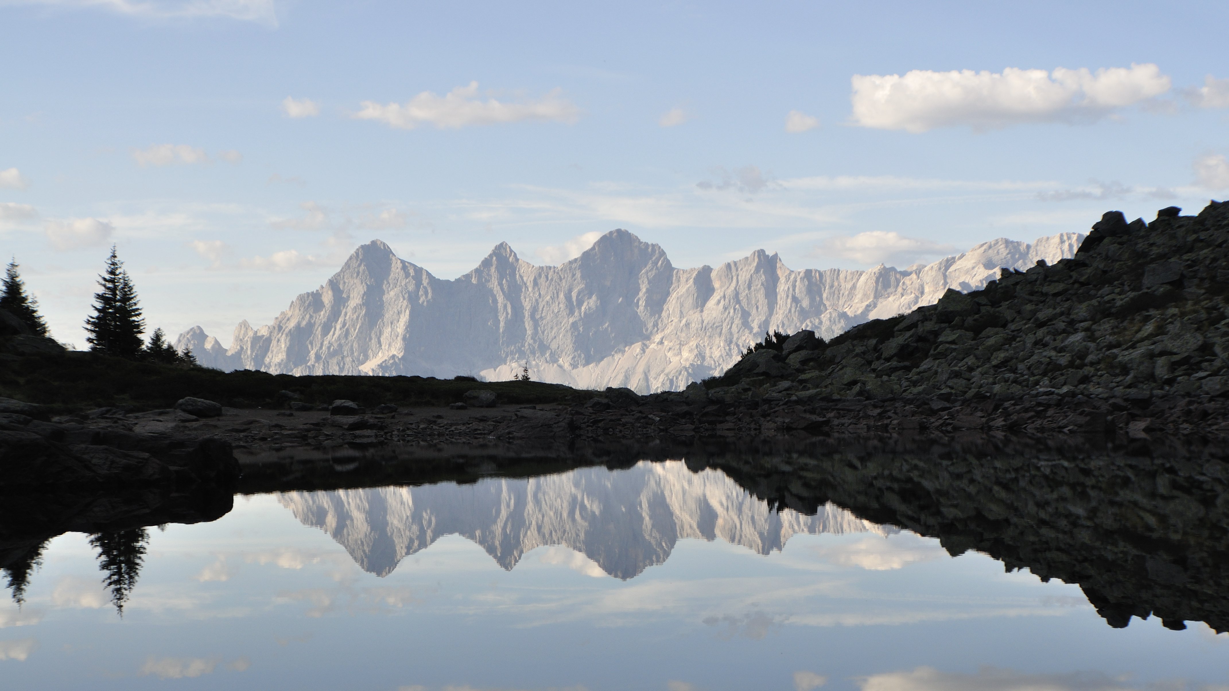 A tranquil lake reflecting surrounding mountains and sky in a natural landscape.