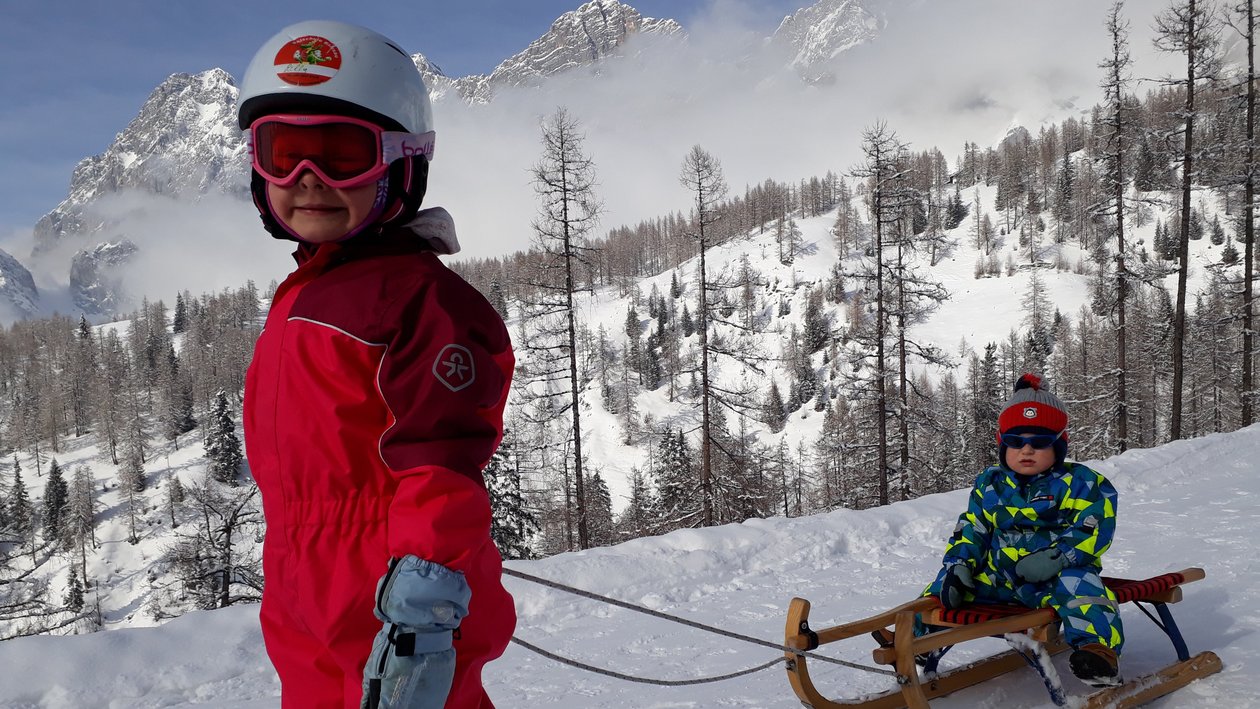 Children playing in deep snow on a winter day in the mountains with trees in background