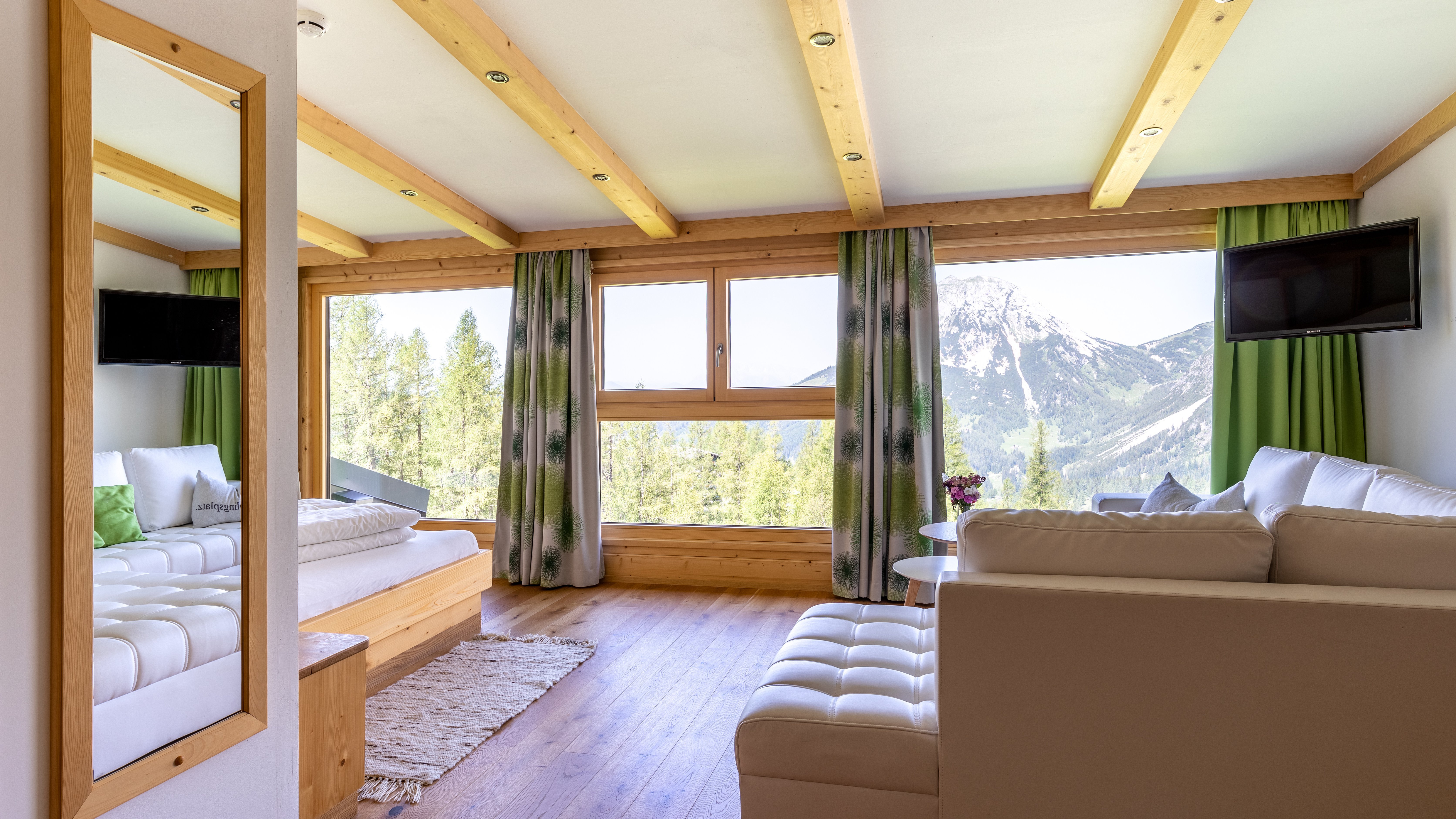Heller Wohnraum mit großen Fenstern und Holzverkleidungen, Blick auf die Berge im Hintergrund.