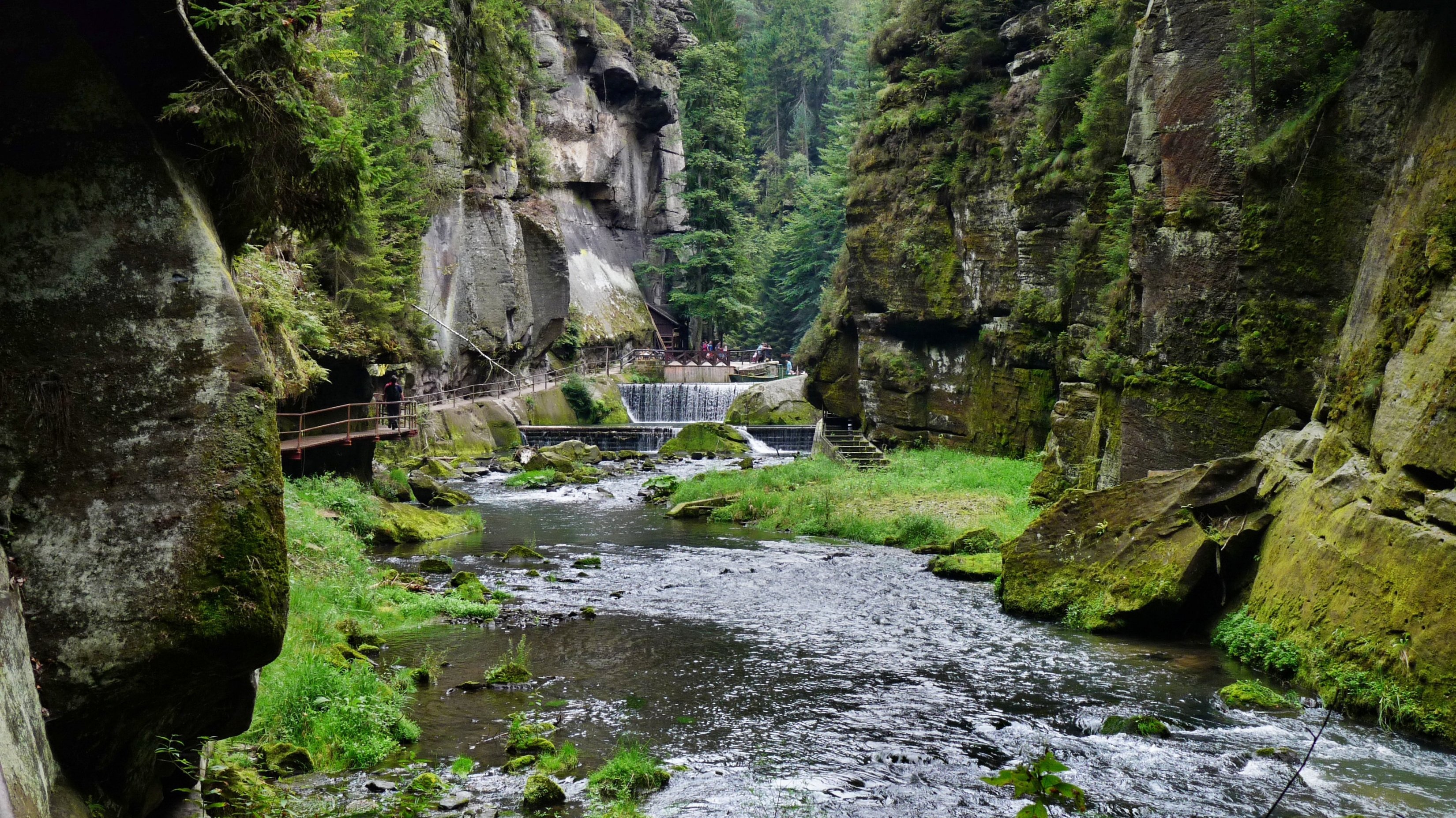 Naturparadies im Canyon Eine ruhige Landschaft mit einem Fluss, der durch einen Canyon fließt, umgeben von üppigem Grün und Moos.