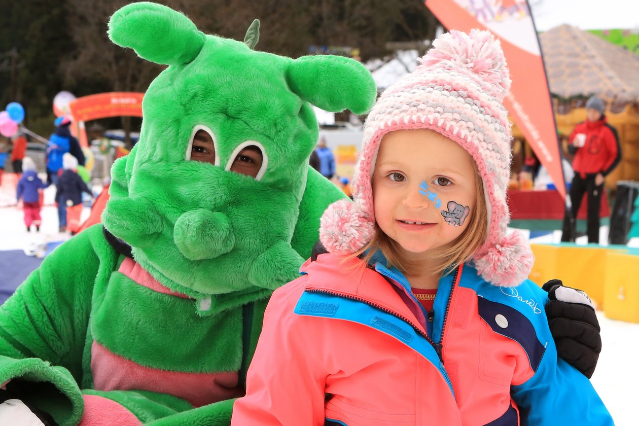 Winterliche Abenteuer für Kinder Ein kostümiertes Charakter und ein Mädchen im Schnee lächeln zusammen in einer winterlichen Landschaft.