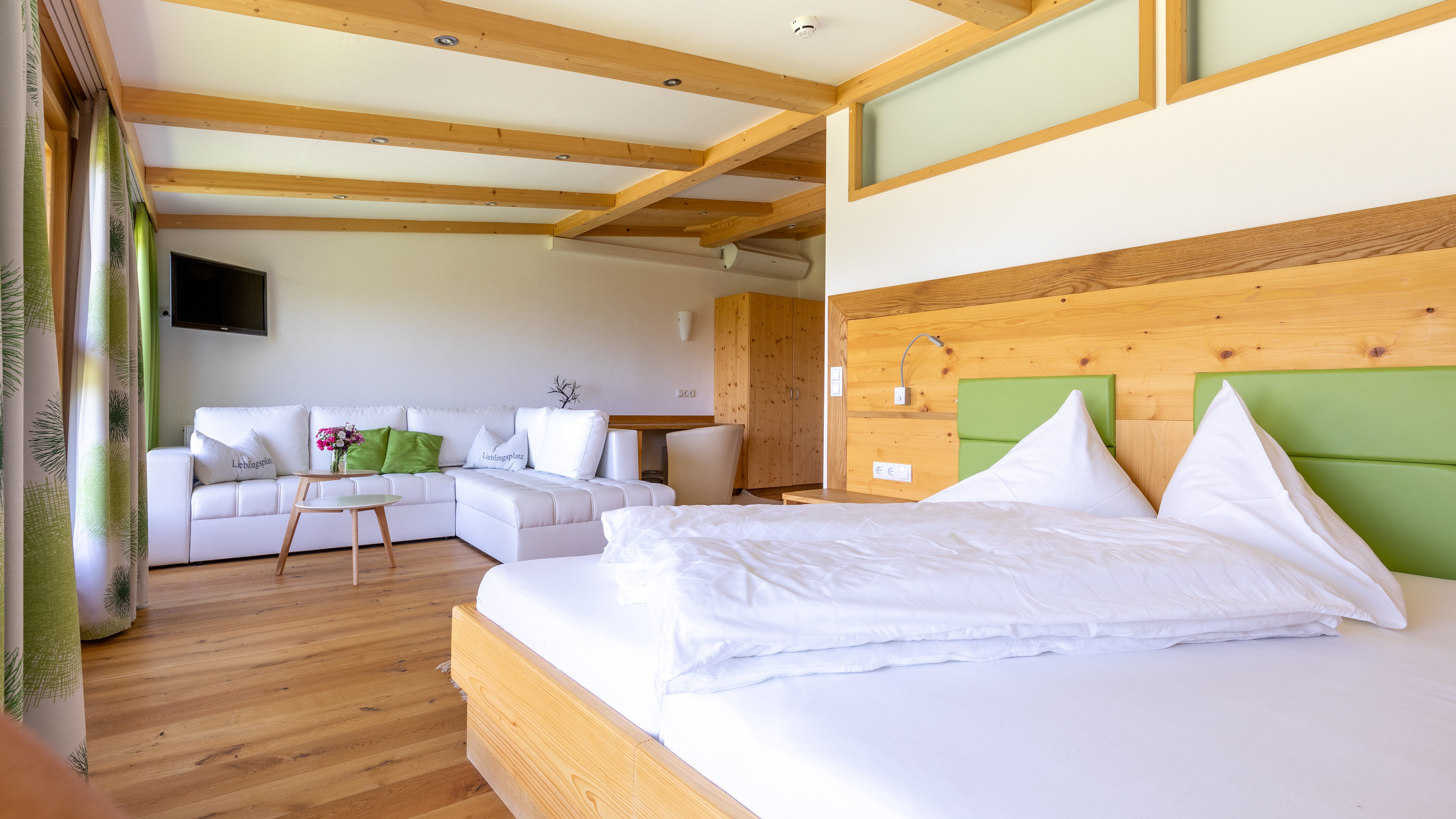 Hotelzimmer mit einem Bett, Loungebereich und Holzverkleidung in der Decke und Möbeln