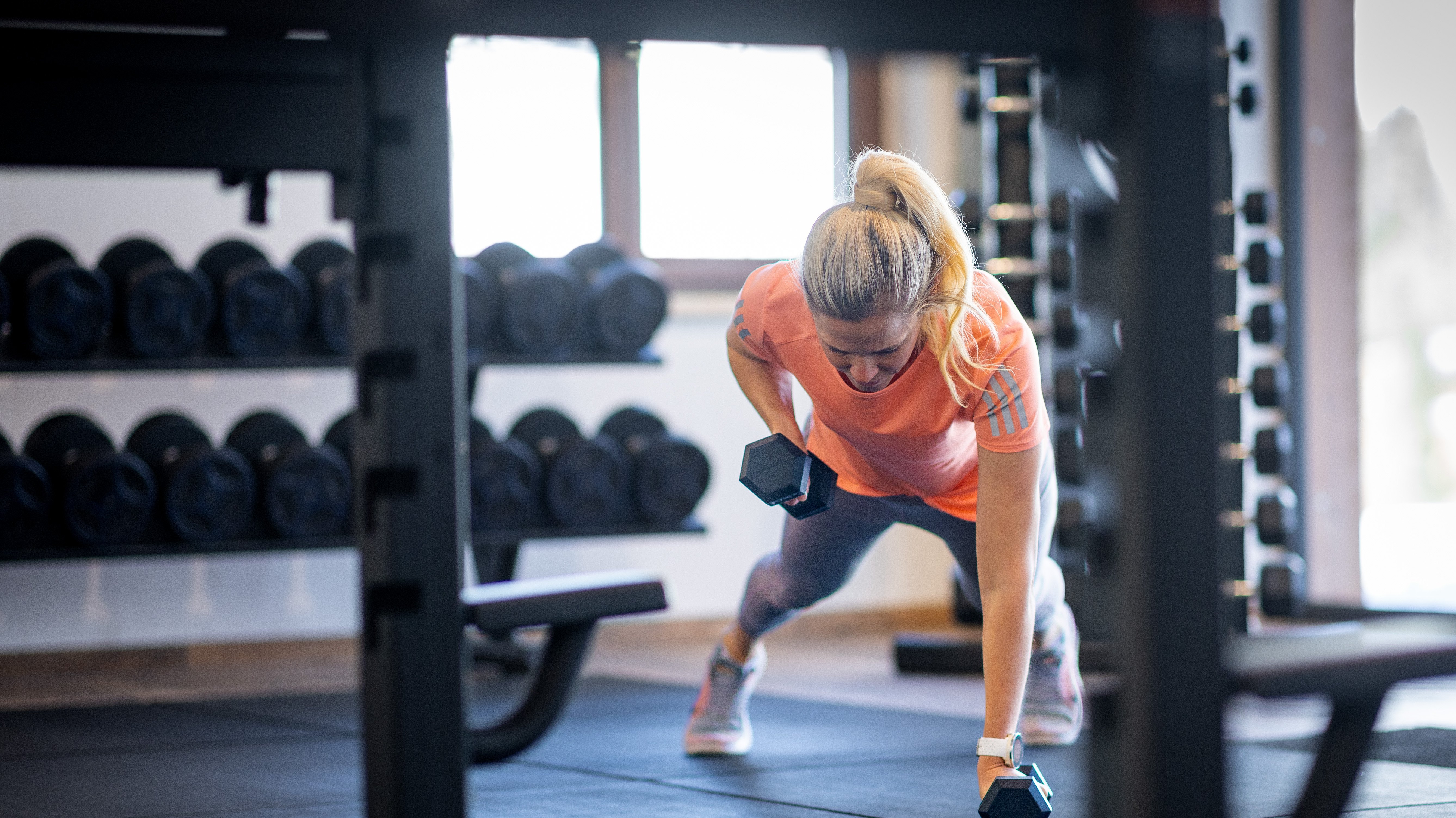 Strength training in a modern gym Woman performing strength training exercise with dumbbells in a fitness room setting