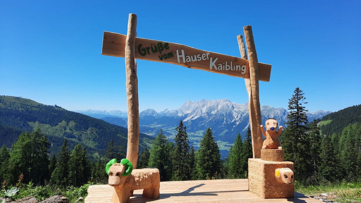 Natürliche Schönheit der Berge Holzschild und Skulpturen in einem gebirgigen Freiluftbereich unter klarem Himmel