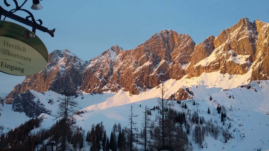 Schneebedeckte Berge mit sonnigen Felsen und einem Eingangsschild im Vordergrund