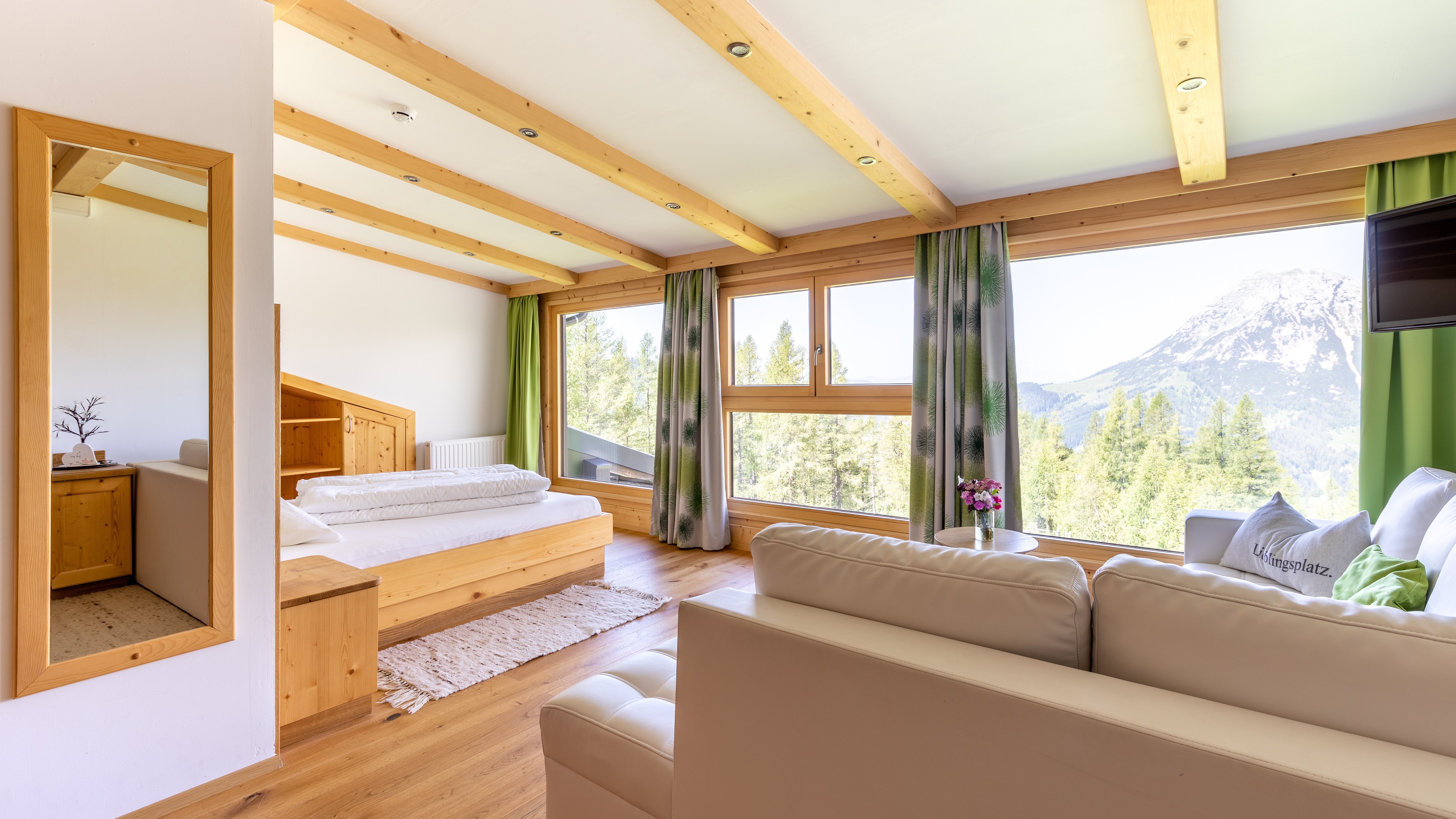 Heller, moderner Wohnraum mit Holzdecke und großen Fenstern, die auf Berge blicken