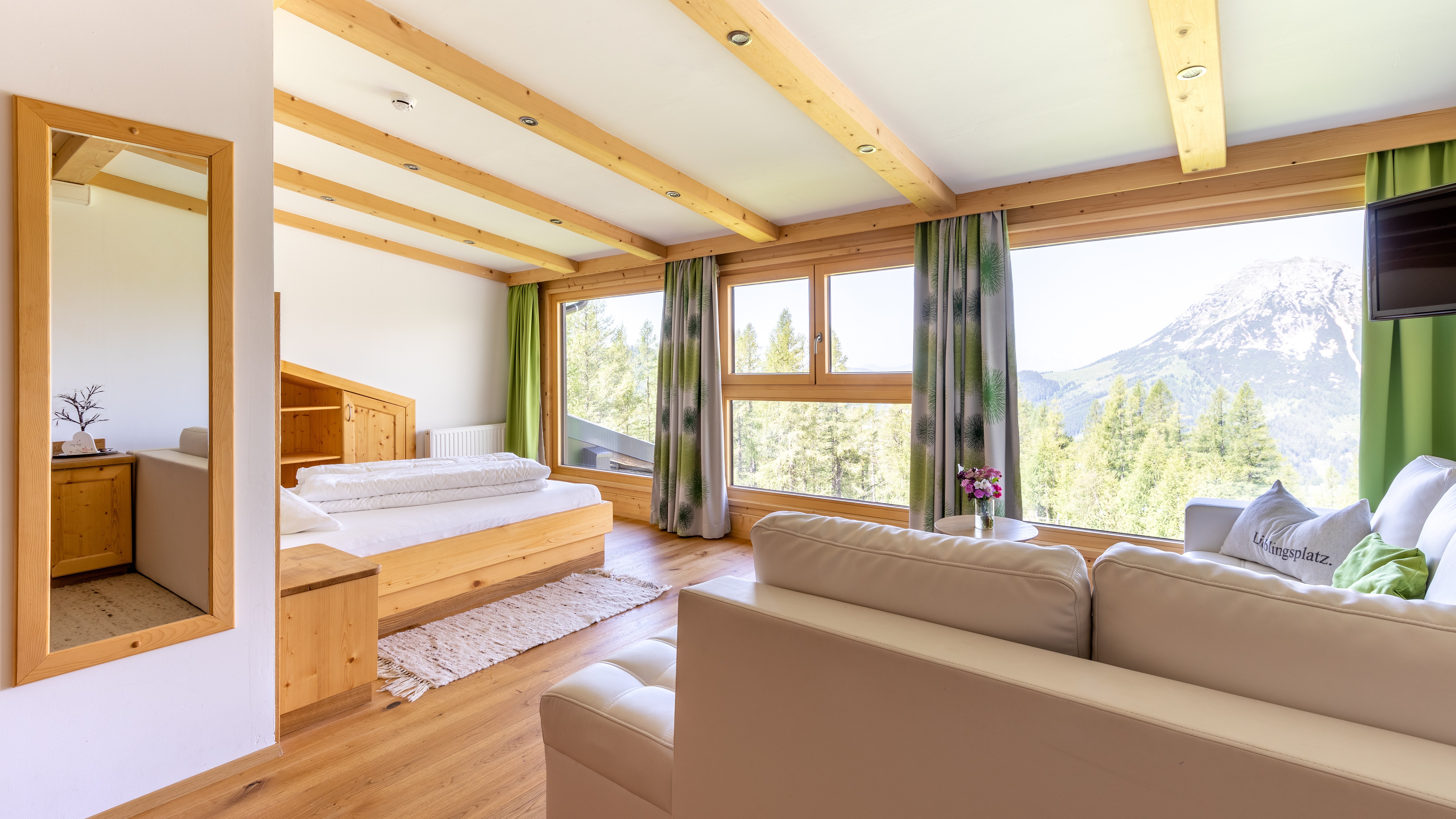 Heller, moderner Wohnraum mit Holzdecke und großen Fenstern, die auf Berge blicken