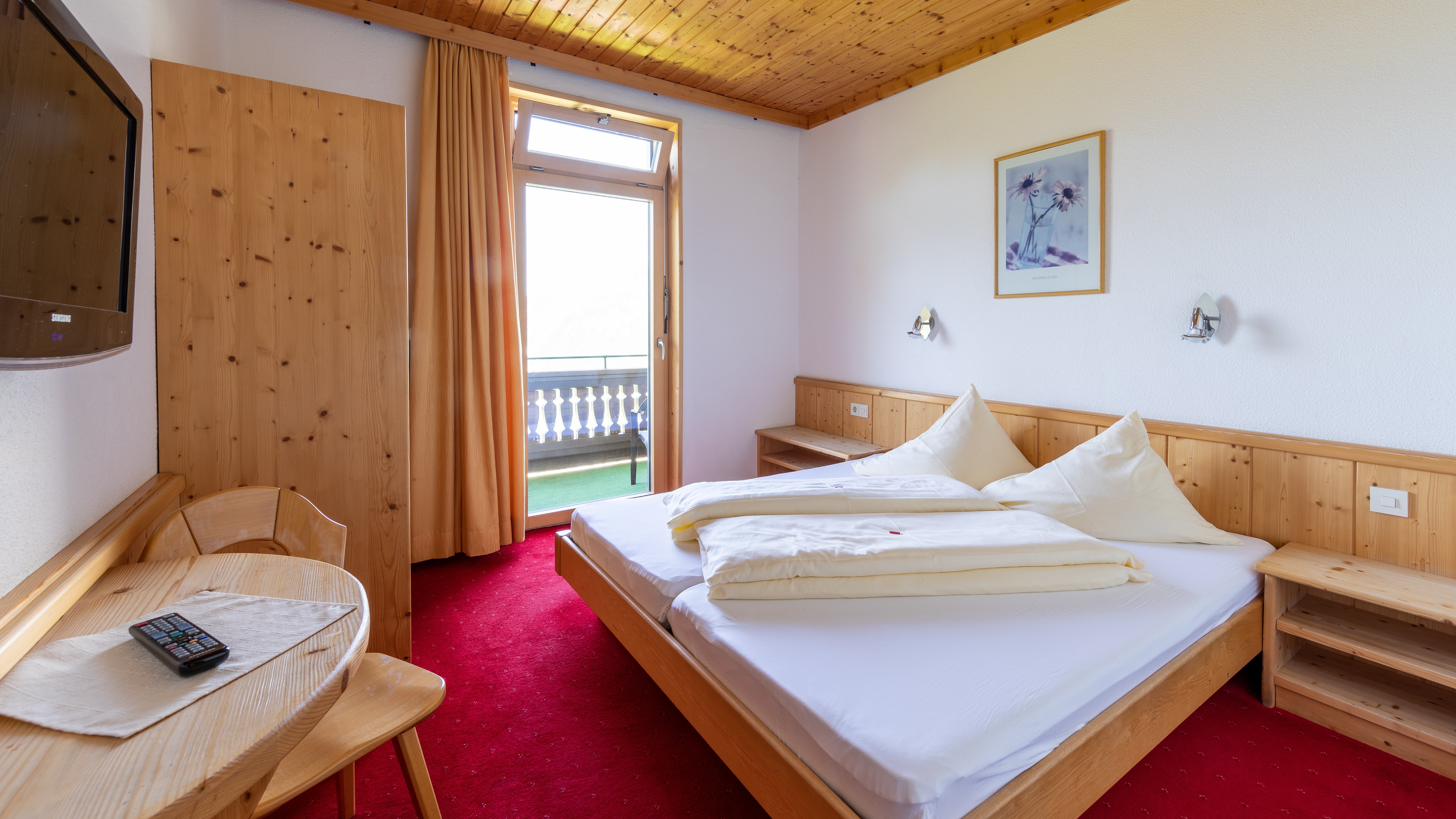 A cozy hotel room featuring wooden furniture and a double bed with a balcony door