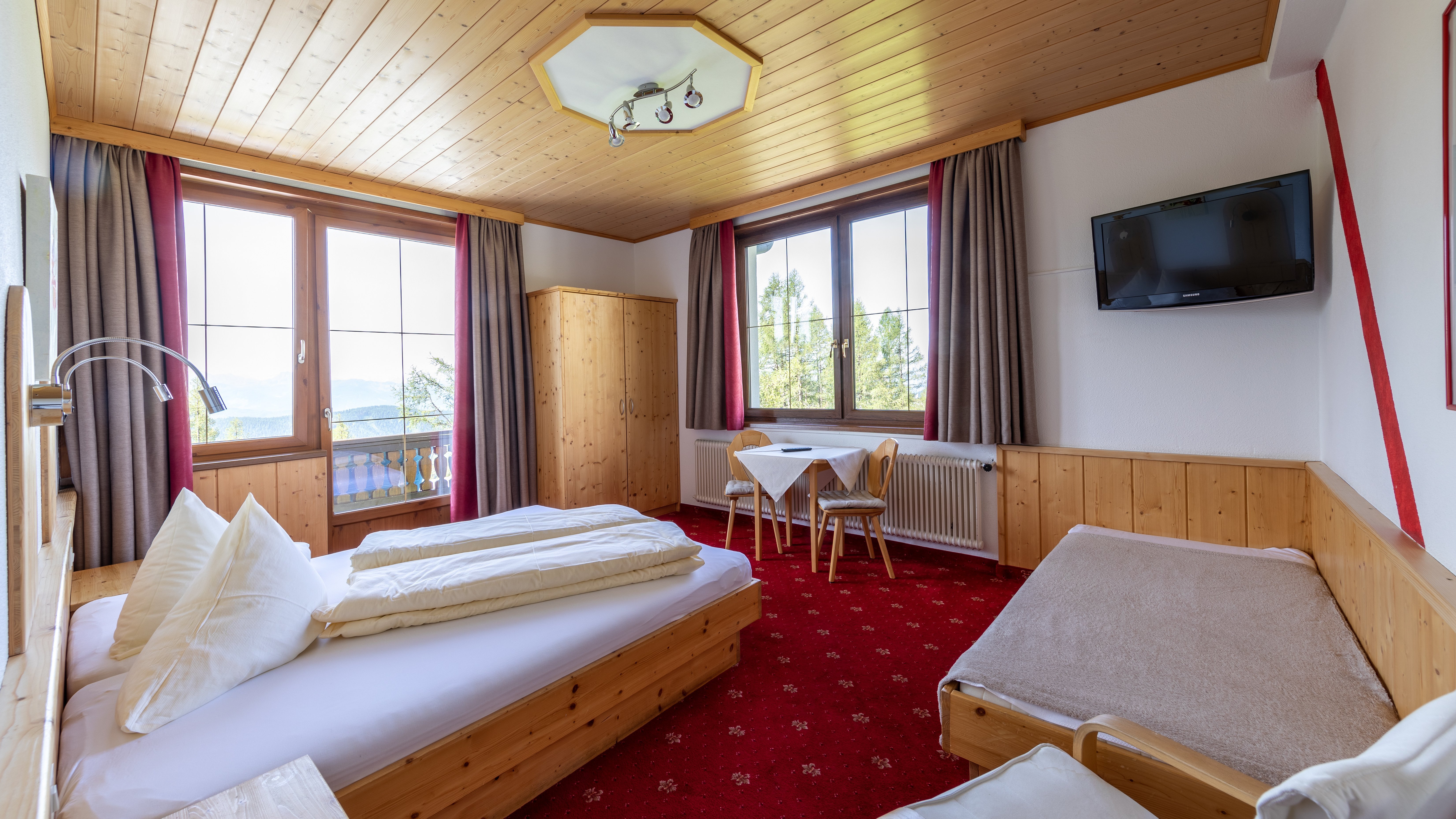 Hotelzimmer mit Holz-Möbeln und großen Fenstern, Blick auf die Berge und einladende Atmosphäre.